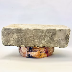 Soft sculpture head crushed by a brick