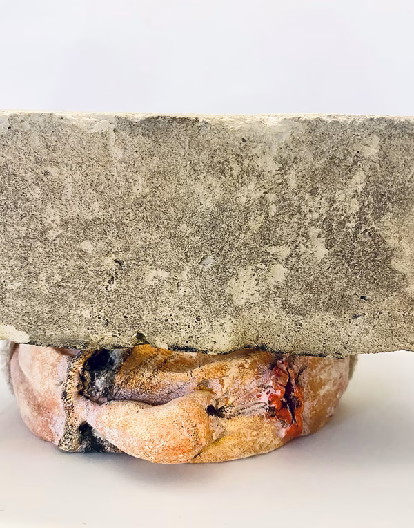 Soft sculpture head crushed by a brick