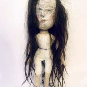 Uncanny girl doll with long dark brown hair.