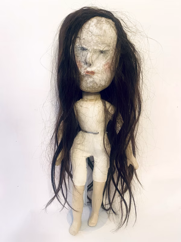 Uncanny girl doll with long dark brown hair.