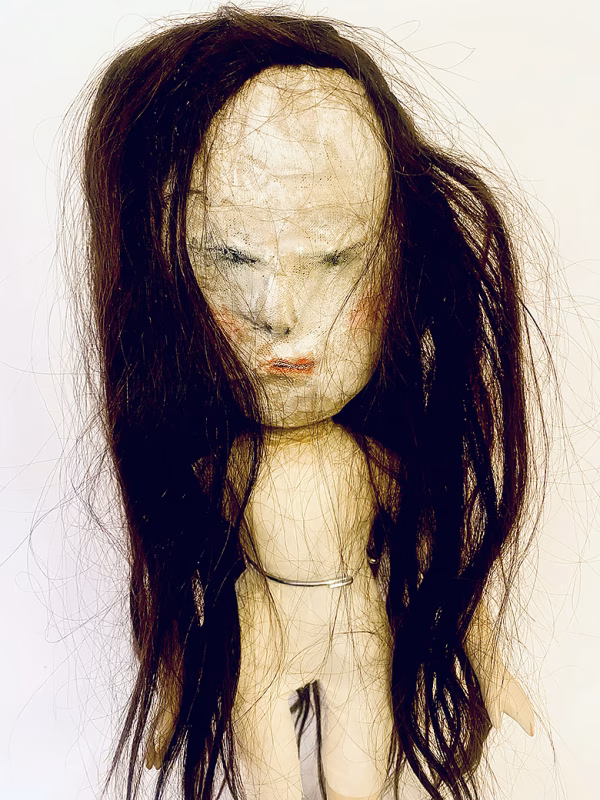Uncanny girl doll with long dark brown hair.