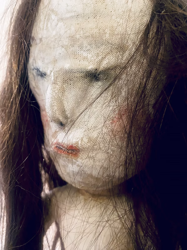 Uncanny girl doll with long dark brown hair. Face detail.