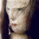 Uncanny girl doll with long dark brown hair. Face detail.