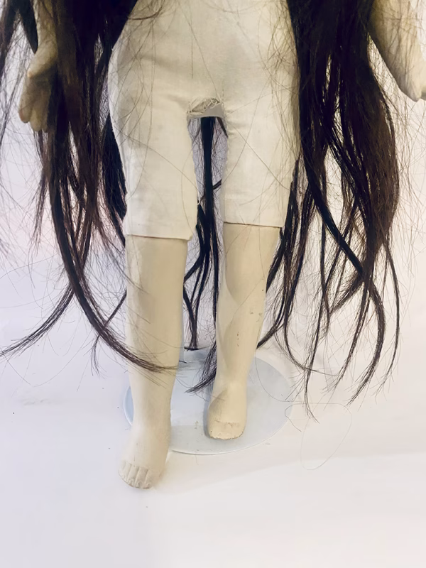 Uncanny girl doll with long dark brown hair. Legs and hips view.