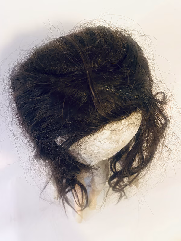 Uncanny girl doll with long dark brown hair. View from above.