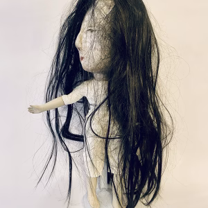 Uncanny girl doll with long dark brown hair.