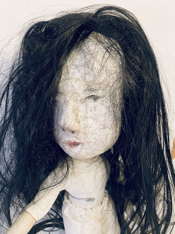 Uncanny girl doll with long dark brown hair.
