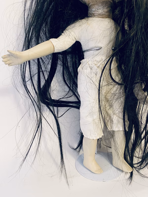Uncanny girl doll with long dark brown hair.
