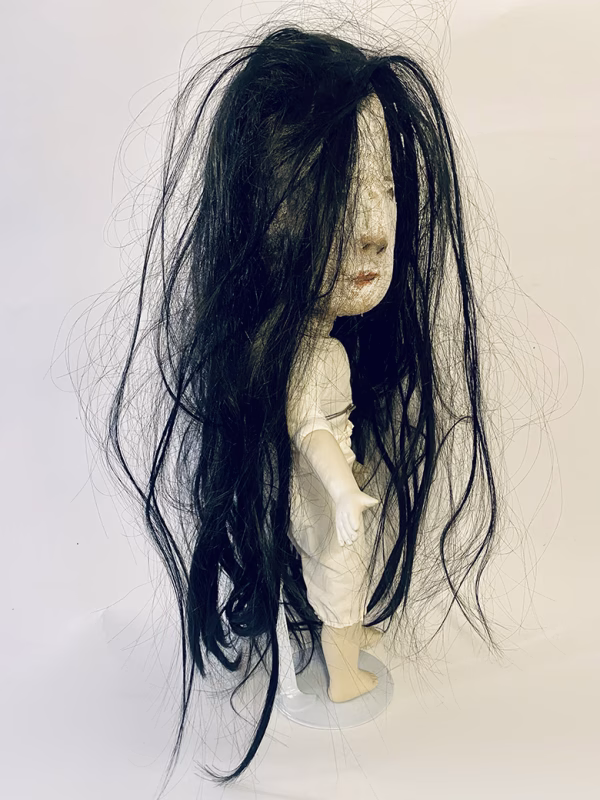 Uncanny girl doll with long dark brown hair.