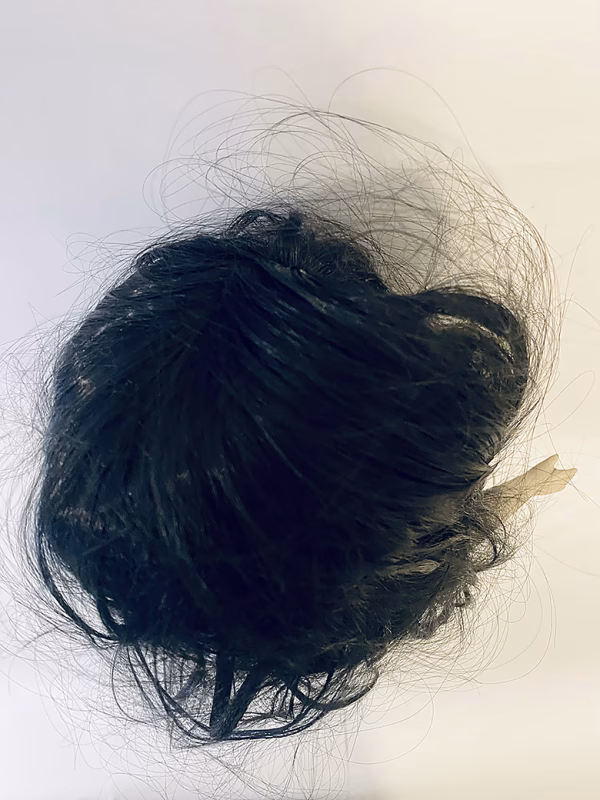 Uncanny girl doll with long dark brown hair. Seen from above.