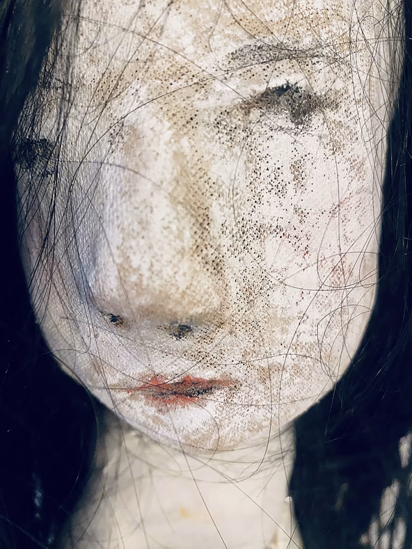 Uncanny girl doll with long dark brown hair. Face detail.