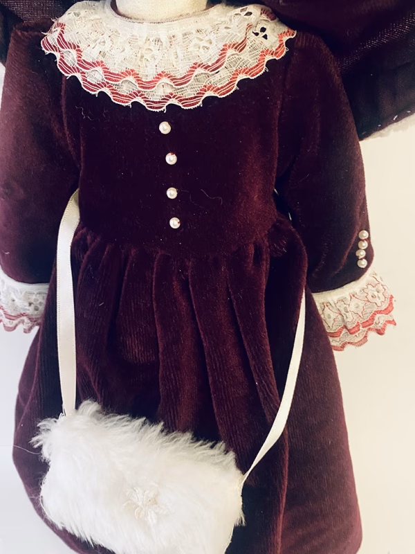 Doll detail: dark red velvet dress with white fur trim and muff.