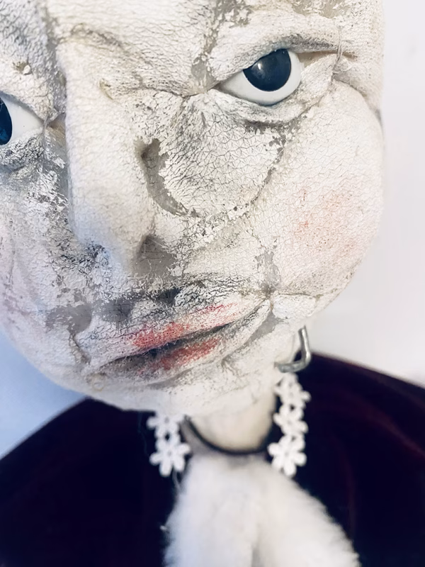 Hacked doll with a Kilner jar clip around its 'ugly' uncanny head.