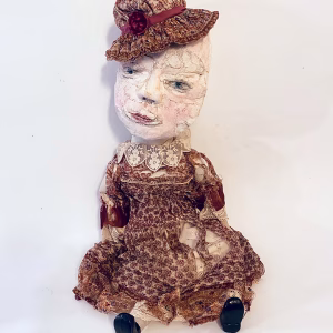 Hacked doll with decayed silk dress. The original ‘pretty’ head is replaced with an oversized, bald, uncanny head.