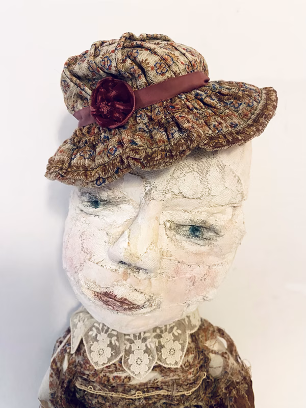 Hacked doll with decayed silk dress. The original ‘pretty’ head is replaced with an oversized, bald, uncanny head.