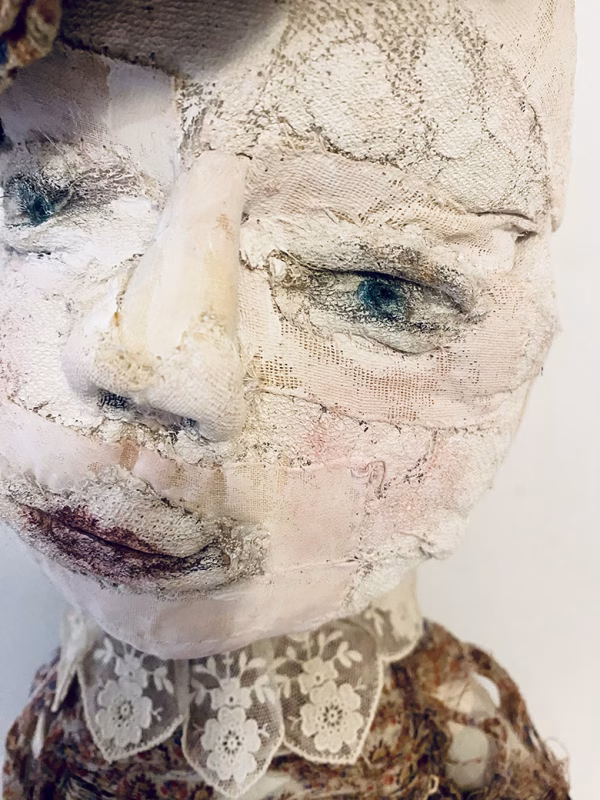 Hacked doll with decayed silk dress. The original ‘pretty’ head is replaced with an oversized, bald, uncanny head.