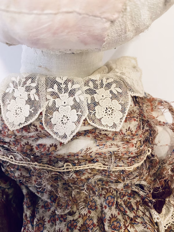 Hacked doll with decayed silk dress. The original ‘pretty’ head is replaced with an oversized, bald, uncanny head.