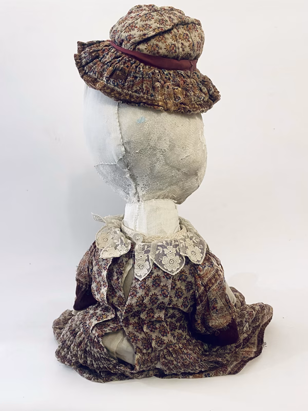 Hacked doll with decayed silk dress. The original ‘pretty’ head is replaced with an oversized, bald, uncanny head.