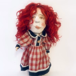Uncanny girl doll with checkered dress and wavy red hair.