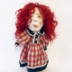 Uncanny girl doll with checkered dress and wavy red hair.