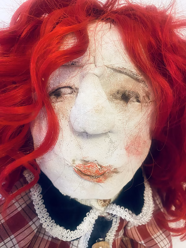 Uncanny girl doll with checkered dress and wavy red hair (face close-up)