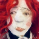 Uncanny girl doll with checkered dress and wavy red hair (face close-up)