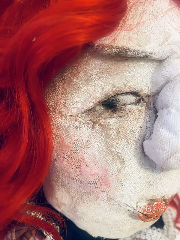 Uncanny girl doll with checkered dress and wavy red hair (face close-up).