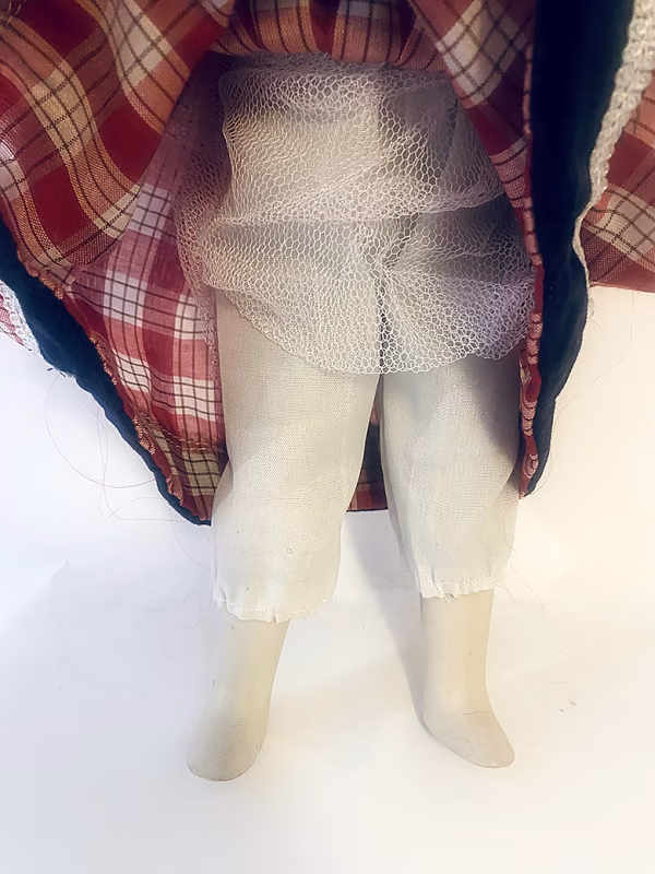 Uncanny girl doll with checkered dress and wavy red hair.