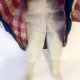 Uncanny girl doll with checkered dress and wavy red hair.