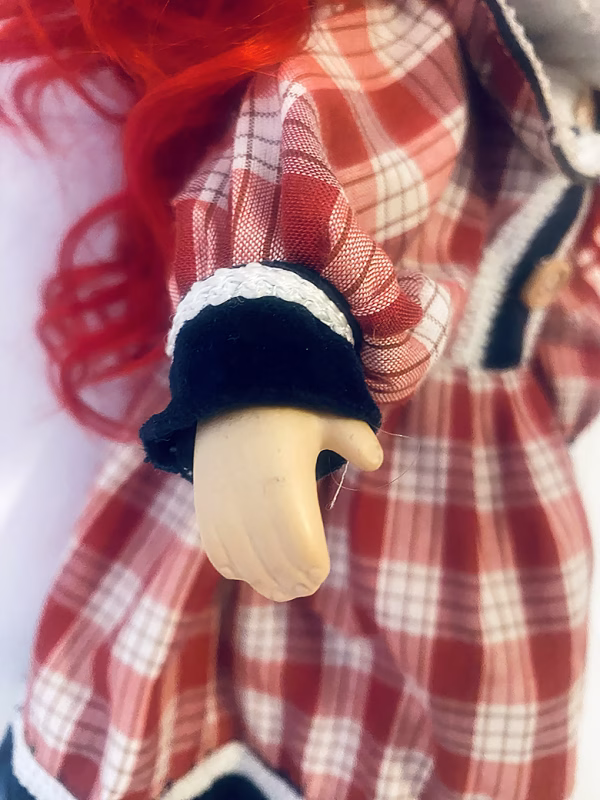 Uncanny girl doll with checkered dress and wavy red hair (detail).