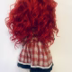 Uncanny girl doll with checkered dress and wavy red hair (back).