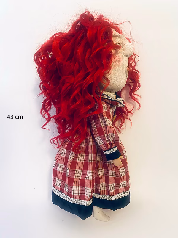 Uncanny girl doll with checkered dress and wavy red hair.