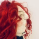 Uncanny girl doll with checkered dress and wavy red hair (face close-up).